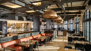 A restaurant with high ceilings, exposed beams, and large windows. There are booths and tables with chairs. - Universal's Hard Rock Hotel (Orlando)