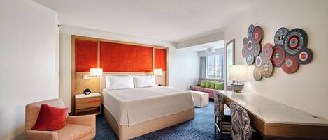 Une chambre d’hôtel avec un grand lit, un bureau, une chaise, une table de chevet et un mur décoré d’assiettes.