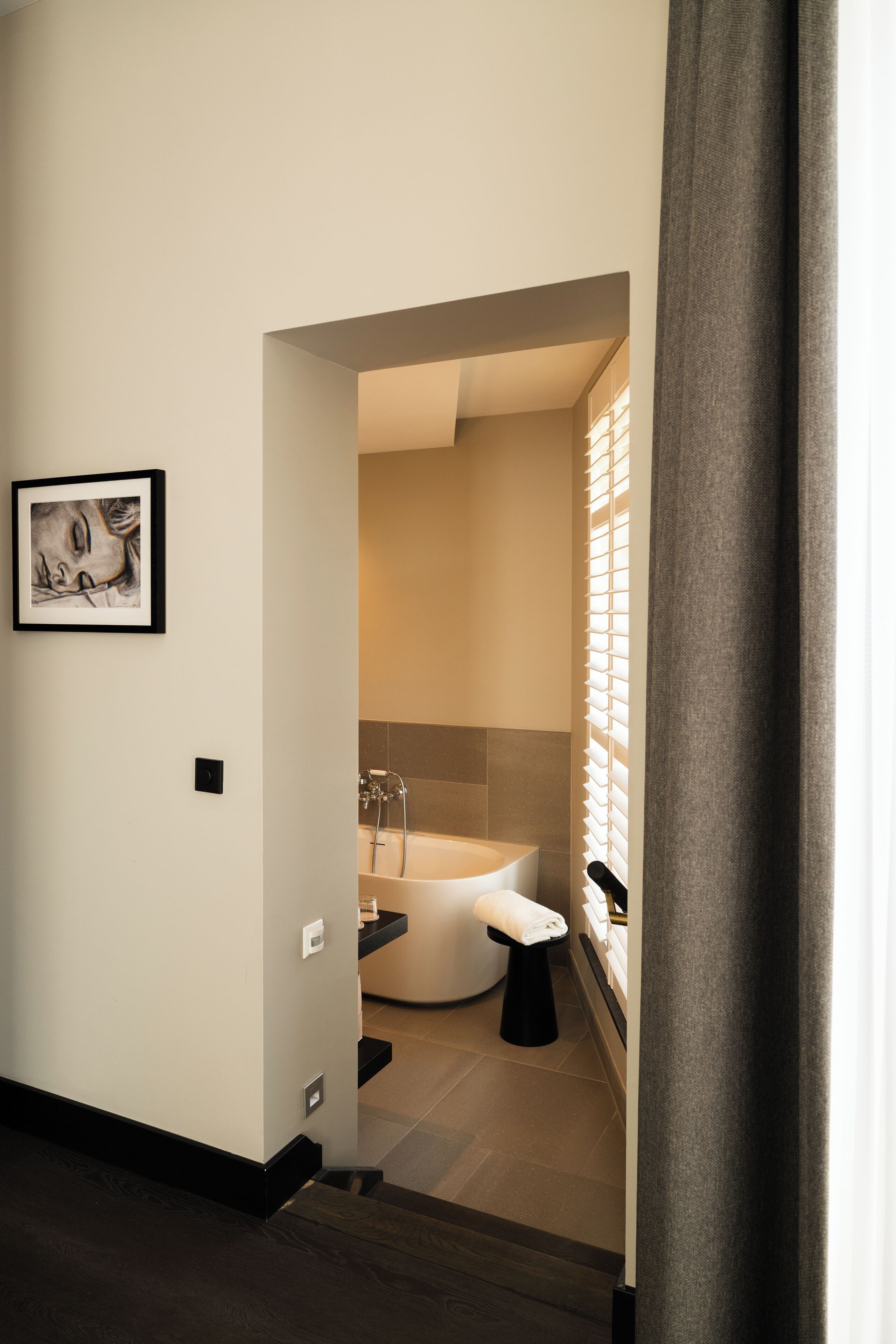 Een moderne badkamer met een vrijstaand bad, een handdoekhouder en een kunstwerk in een lijst op de muur.