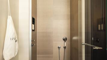Eine moderne Dusche mit Glastür, ein Handtuch an der Wand und ein sichtbares Bedienfeld.