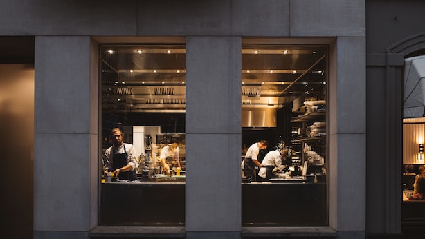Una cocina moderna con ventanas amplias, equipo de cocina a la vista y una persona trabajando.