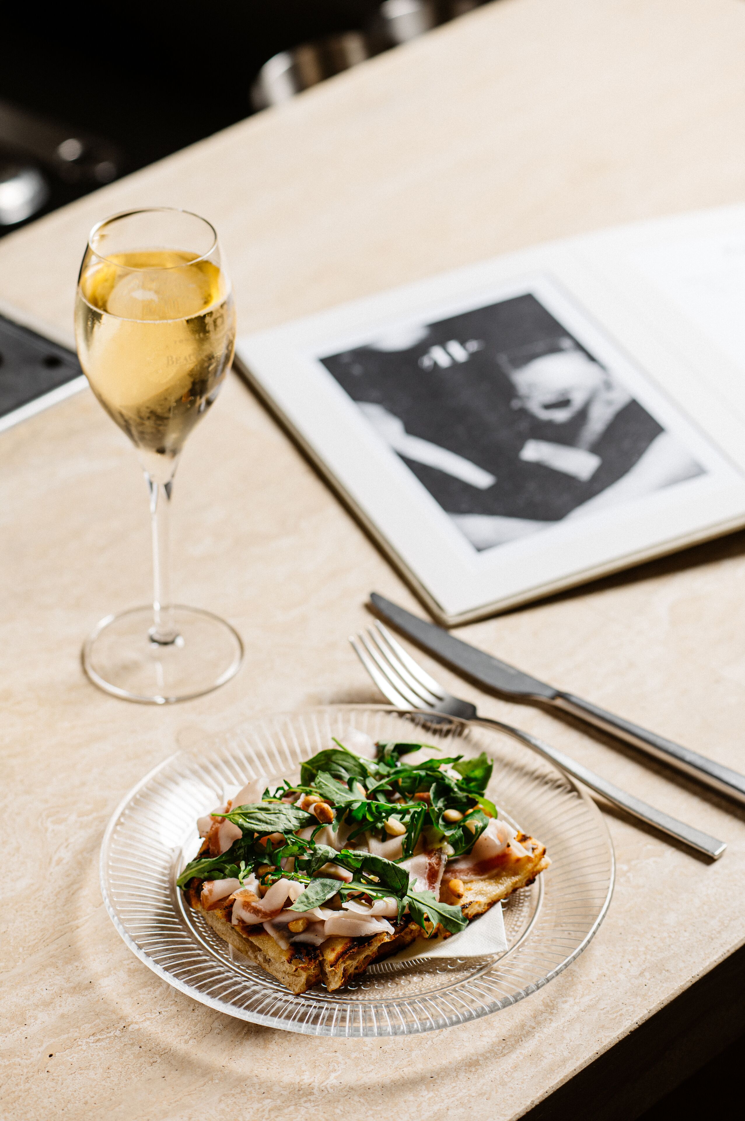 Een bord eten met een glas witte wijn op een tafel.