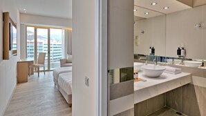 A modern hotel bathroom with a large mirror, a white sink, and a shower.