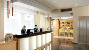 A hotel reception area with a modern design, featuring a reception desk, a bar area, and a seating section.