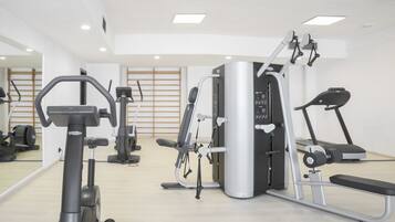 Ein Fitnessstudio mit verschiedenen Trainingsgeräten, darunter Laufbänder, ein Crosstrainer und Kraftgeräte.