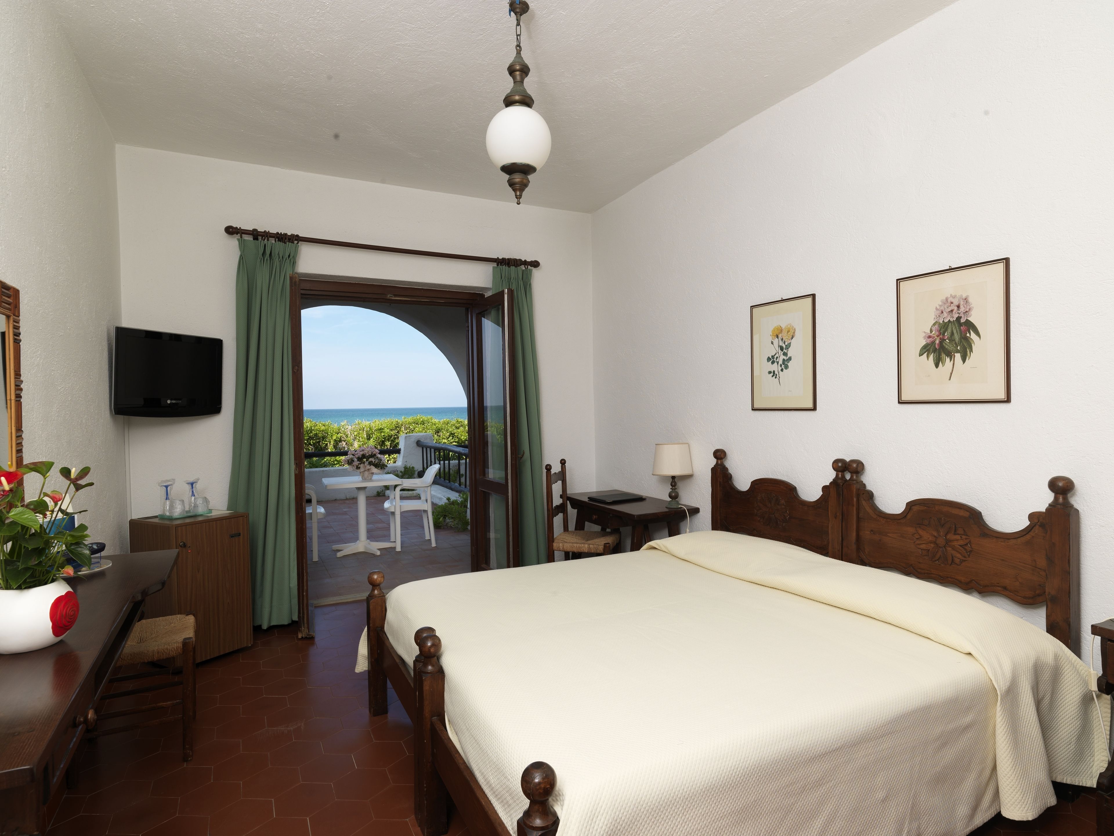 Ein Schlafzimmer mit Bett, Schreibtisch, Stuhl, Fernseher und einem Balkon mit Blick.