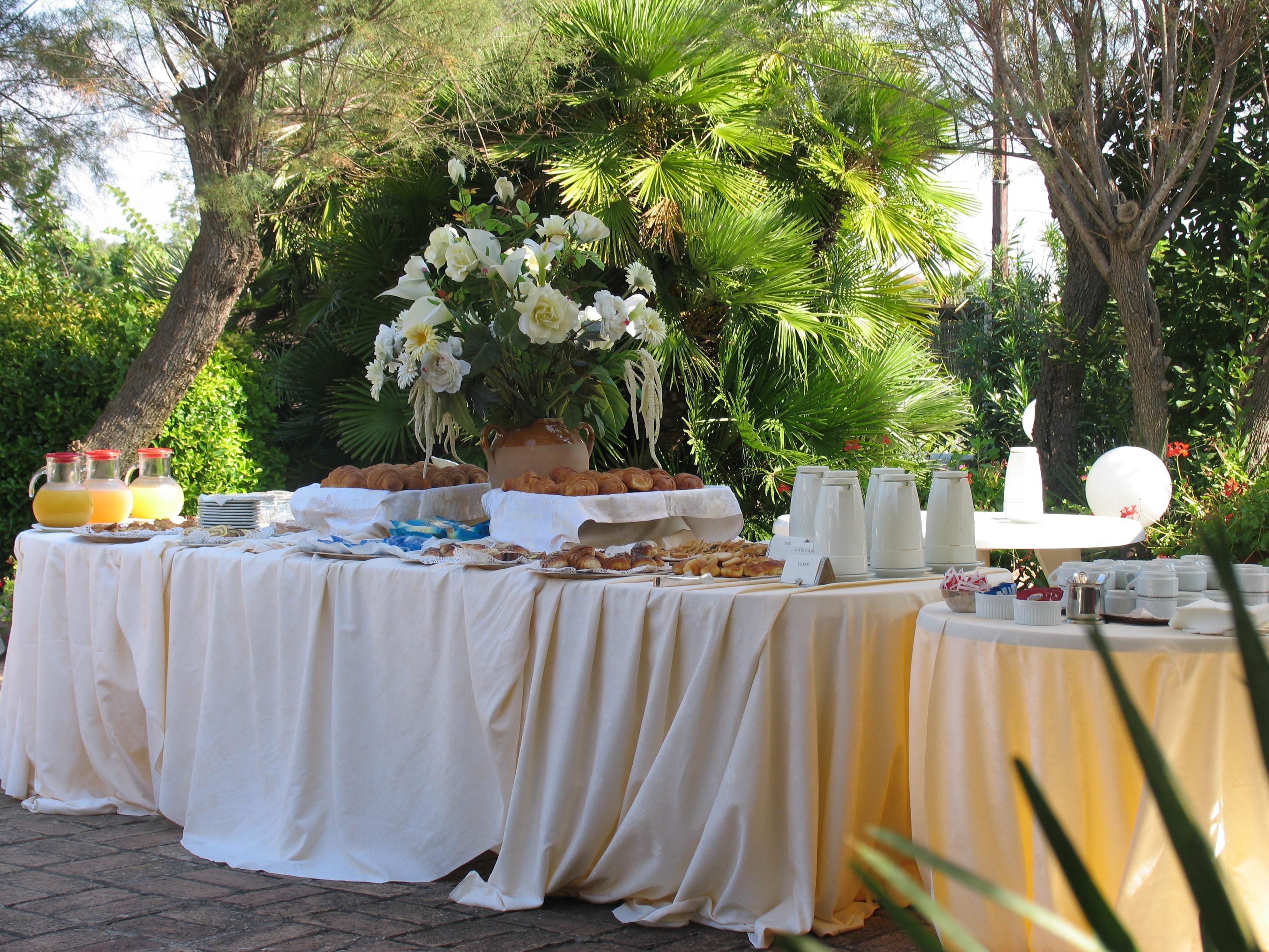 Una mesa de buffet al aire libre con diversas opciones de comida y un centro de mesa floral.