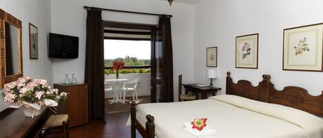 A bedroom with a wooden bed, a desk, a chair, a TV, and a balcony with a view.