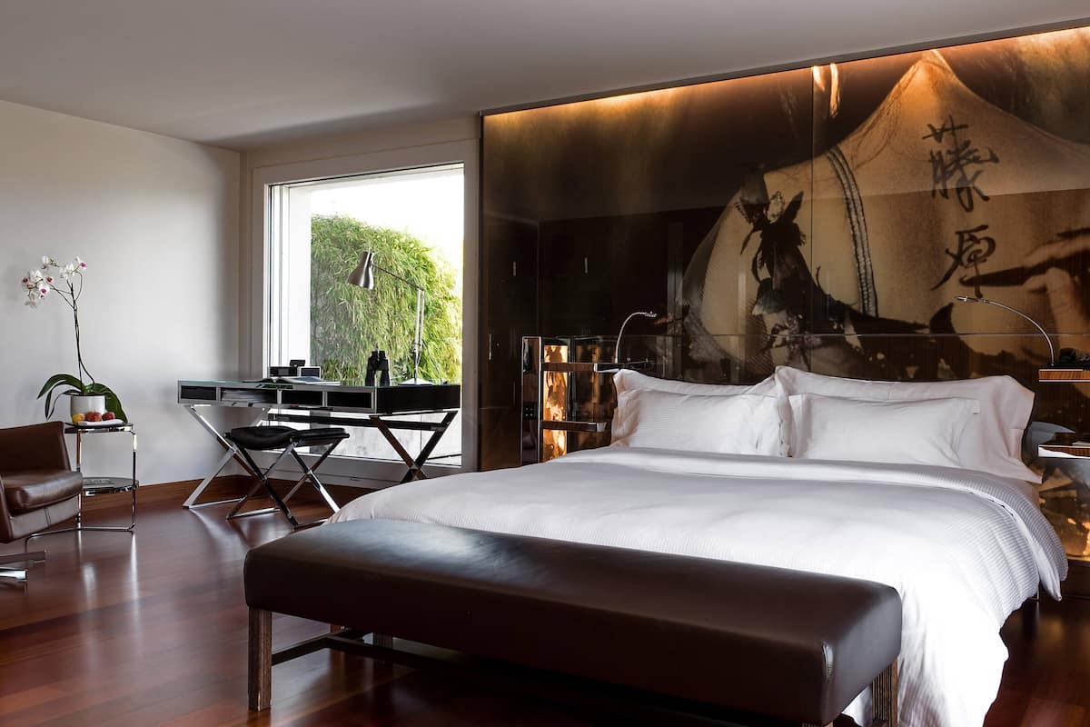 A modern bedroom with a large bed, a desk, and a chair.