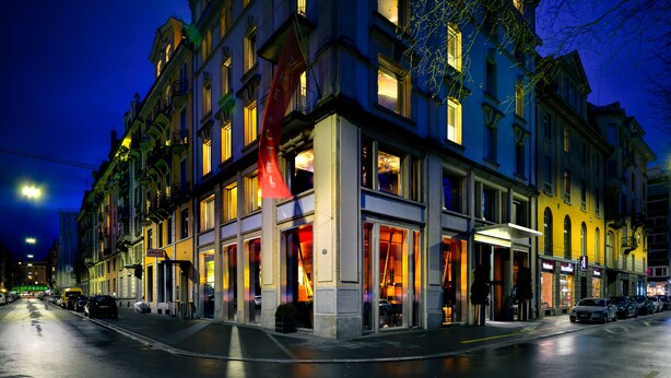 A multi-story hotel with large windows and a prominent red flag on the facade. - The Hotel Luzern, Autograph Collection (Lucerne)