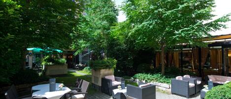 Un patio al aire libre con muebles de mimbre, una mesa y una planta en maceta.