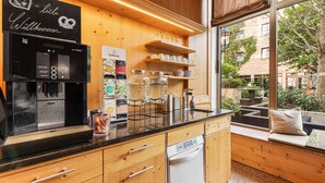 Una cocina moderna con armarios de madera, encimera negra y un ventanal con vistas al exterior.