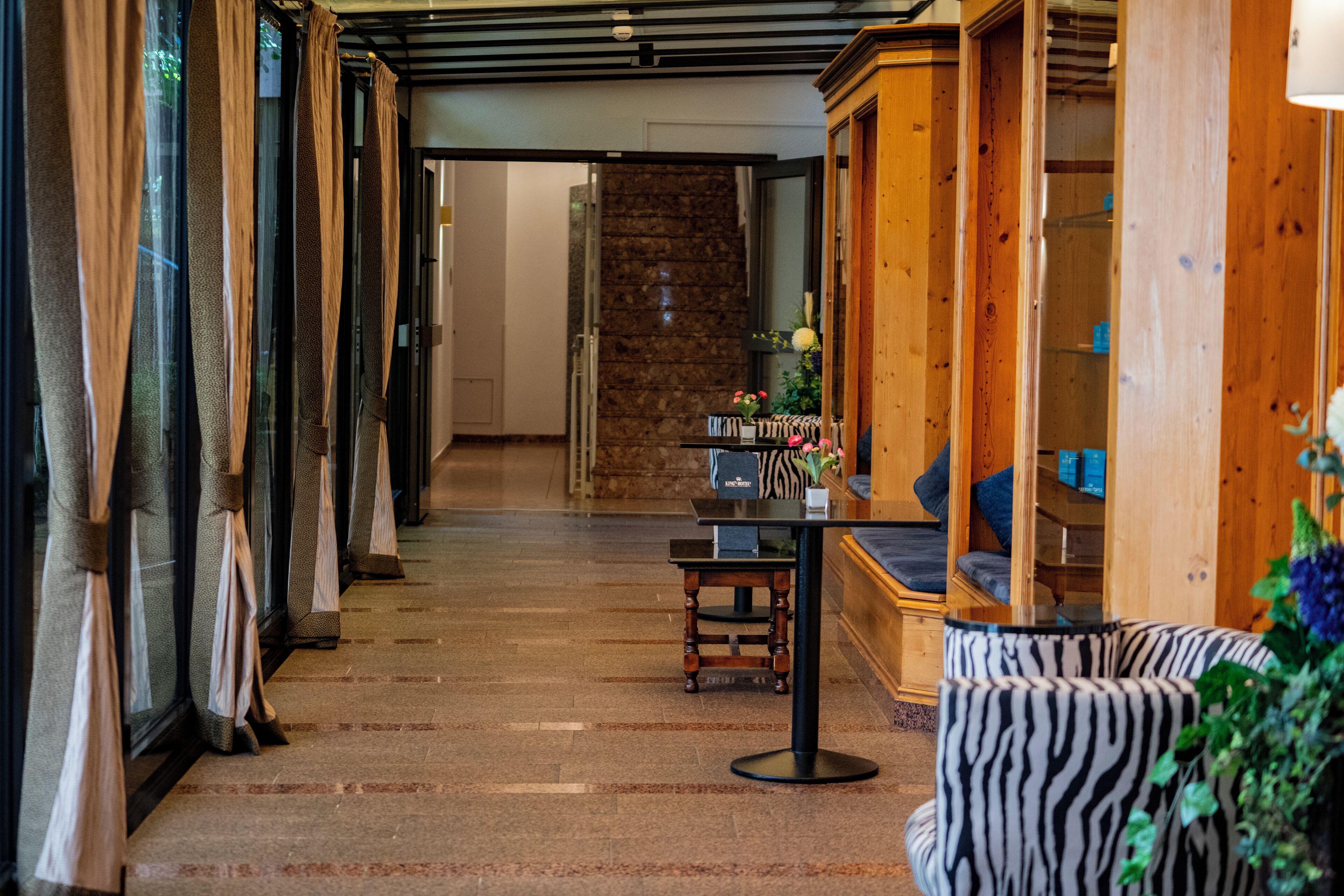 Vestíbulo de hotel con escalera, mostrador de recepción y zonas de estar.