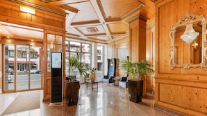 Un vestíbulo con paneles de madera, mostrador de recepción, zona de estar y un espejo grande.
