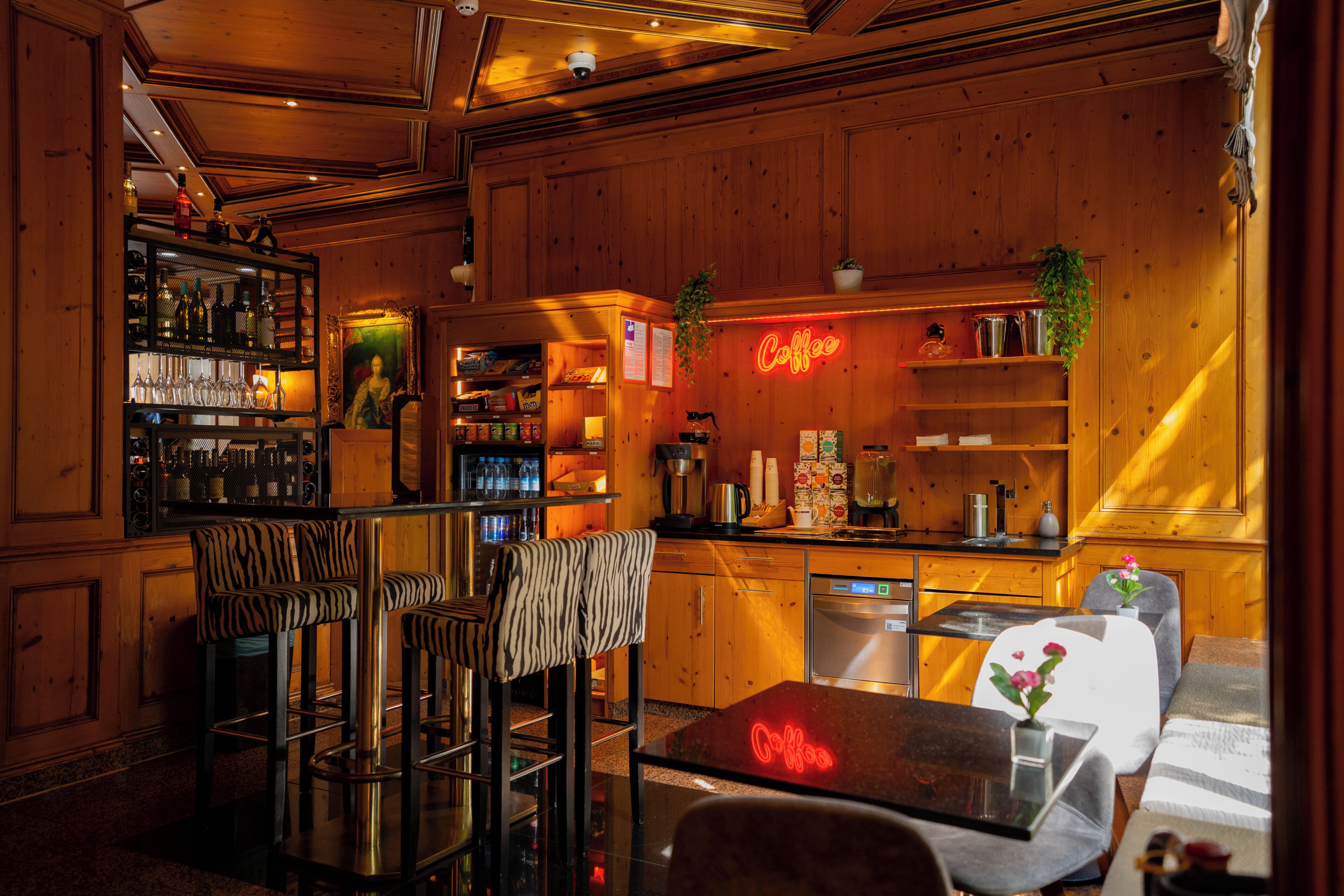 Zona de bar con paneles de madera, taburetes y una señal de neón.