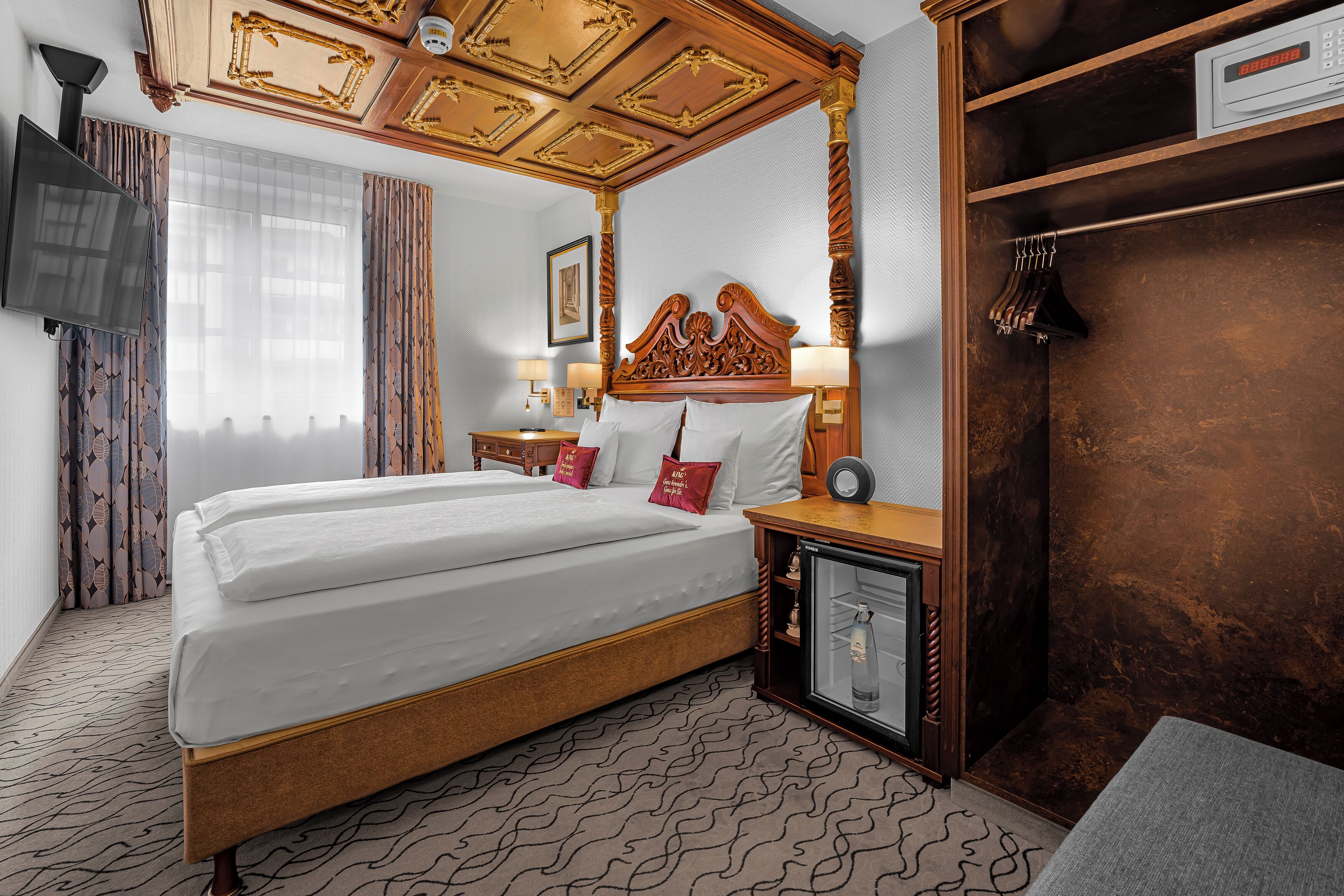Hotelkamer met een baldakijnbed, een minibar, een televisie en een kledingkast.