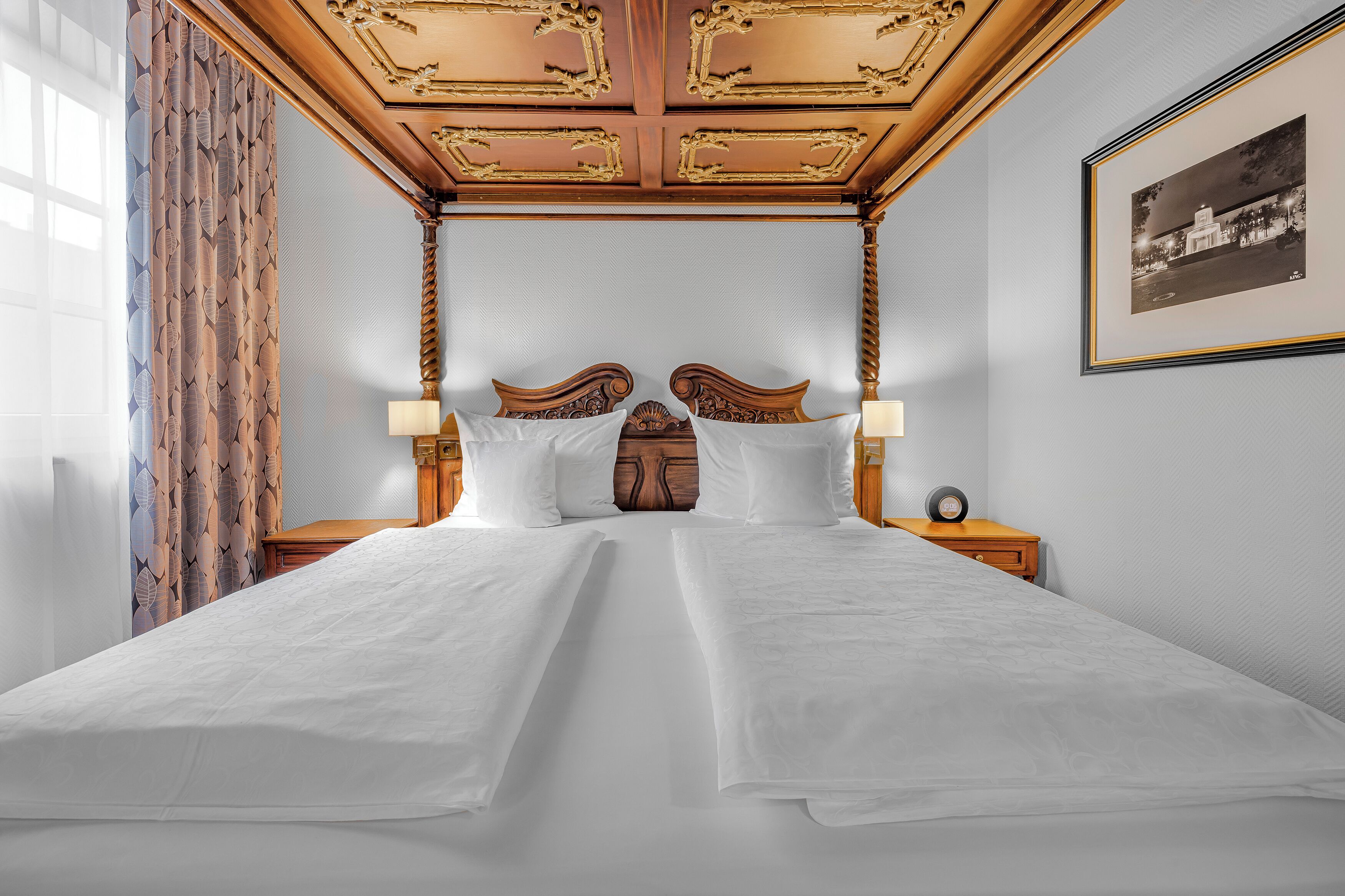 A double bed with a wooden headboard, two bedside tables with lamps, and a framed picture on the wall.