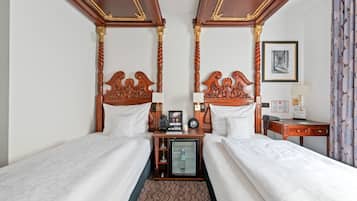 A hotel room with two beds, a minibar, a desk, and a framed picture on the wall.