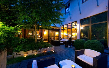 An outdoor patio area with wicker furniture, a table with a candle, and a view of the interior through glass doors.