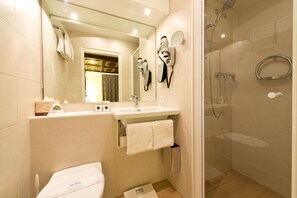 Un baño moderno con ducha de vidrio, lavamanos con toallero y retrete.