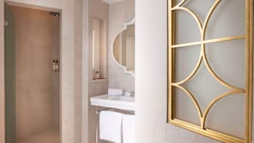 A modern bathroom with a shower, sink, and decorative mirror.