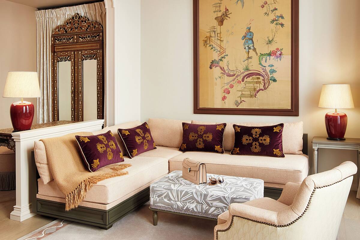 A living room with a sofa, armchairs, a coffee table, a large mirror, and a painting on the wall.