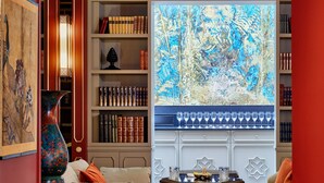 Ein gemütliches Arbeitszimmer mit Bücherregalen, einem großen Fenster mit Gemälde und einer Sitzecke mit Couchtisch.