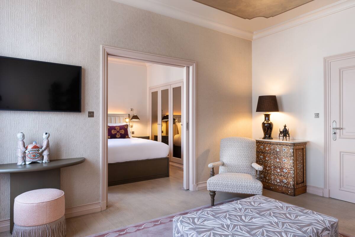 A hotel room with a bed, a TV, a chair, a small table, and a cabinet.