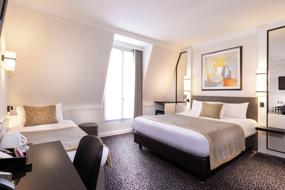 A hotel room with two beds, a desk, a chair, a TV, and a painting on the wall.