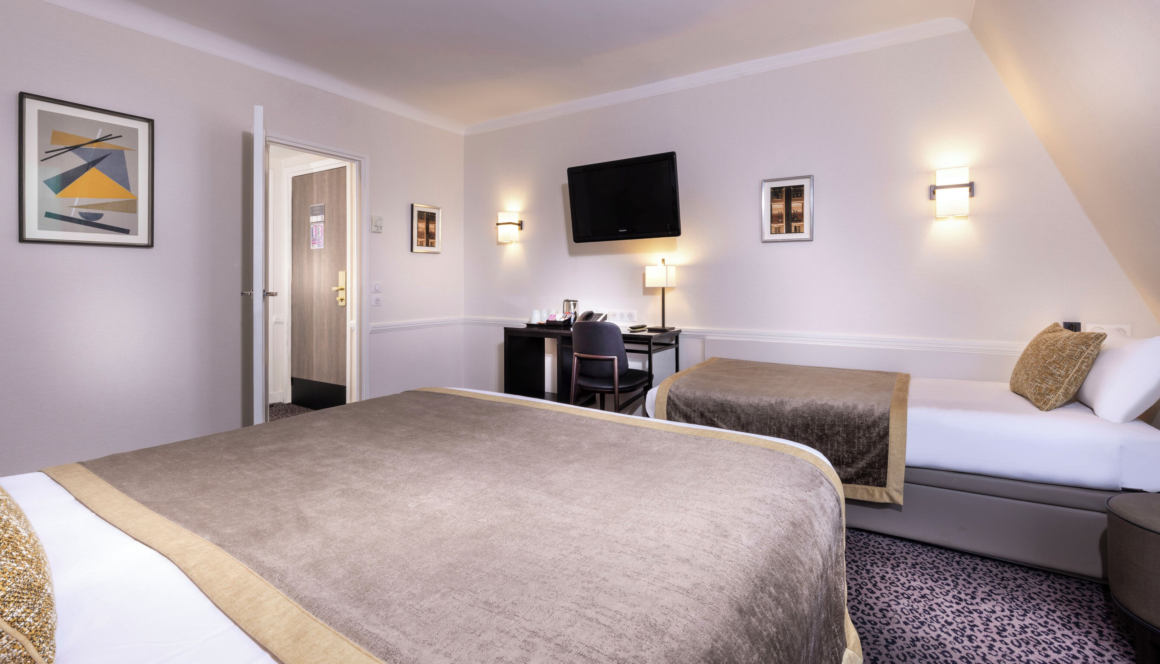 Habitación de hotel con cama, escritorio con silla, televisor y puerta que da a un baño.