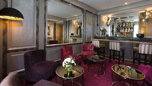 A bar area with seating, a mirrored wall, and a bar stocked with bottles. - Elysees Union Hotel (Paris)