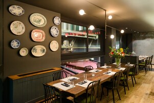 A restaurant with a long wooden table set for dining, surrounded by chairs.