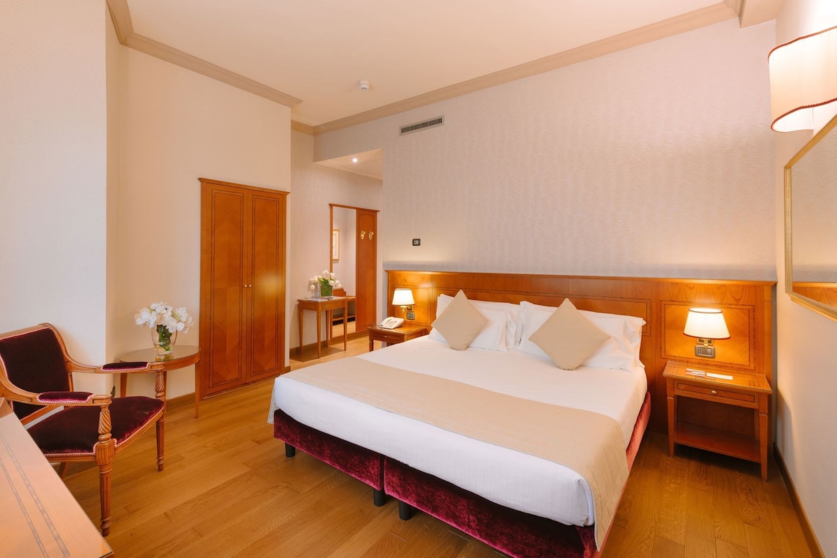 Habitación de hotel con una cama grande, muebles de madera, un escritorio y una silla.