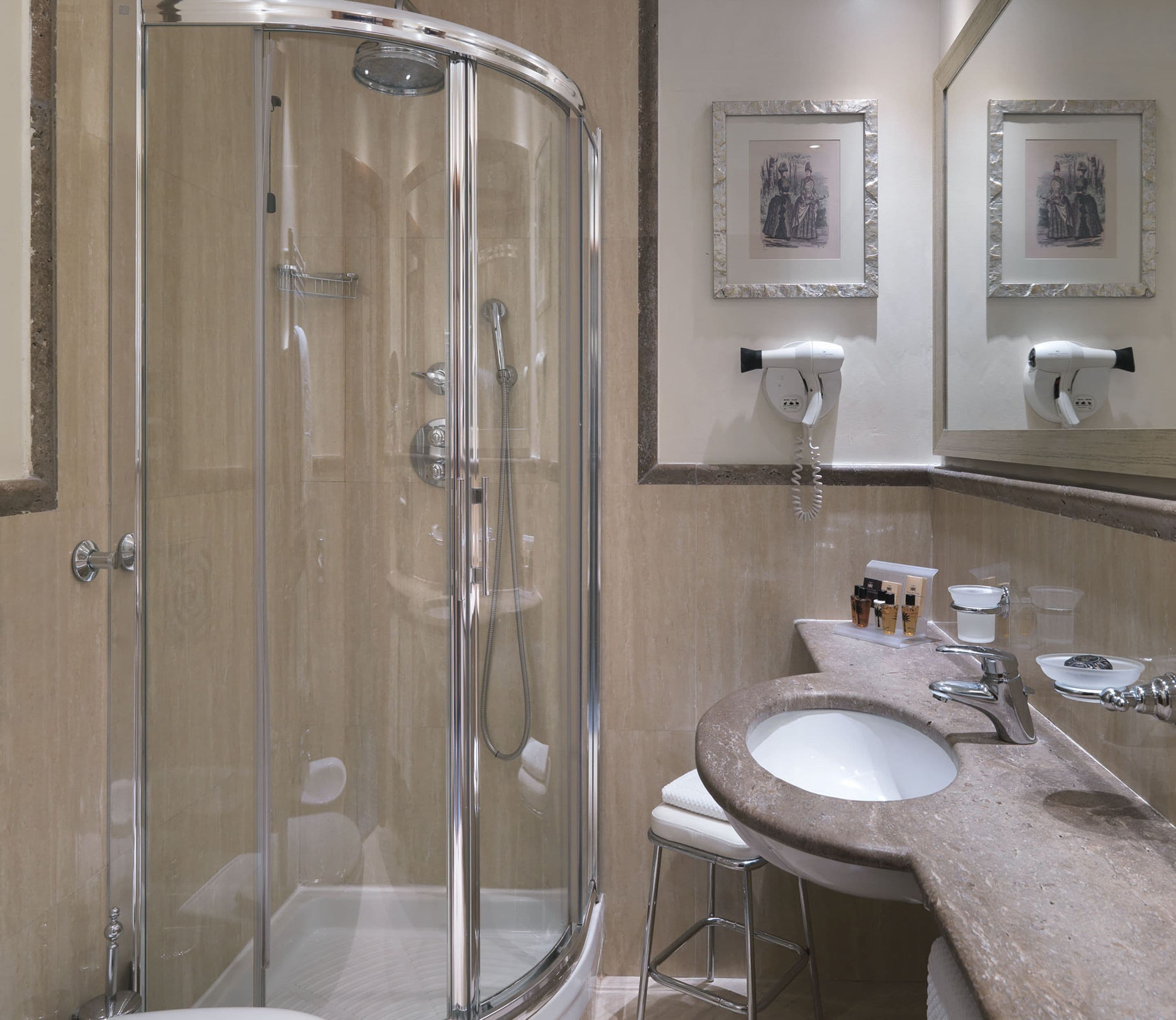 Ein modernes Badezimmer mit einer Duschkabine, einem Waschbecken mit Marmorplatte und zwei gerahmten Bildern an der Wand.