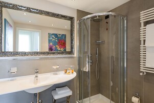 Een moderne badkamer met een douchecabine van glas, een grote spiegel en een witte wasbak.