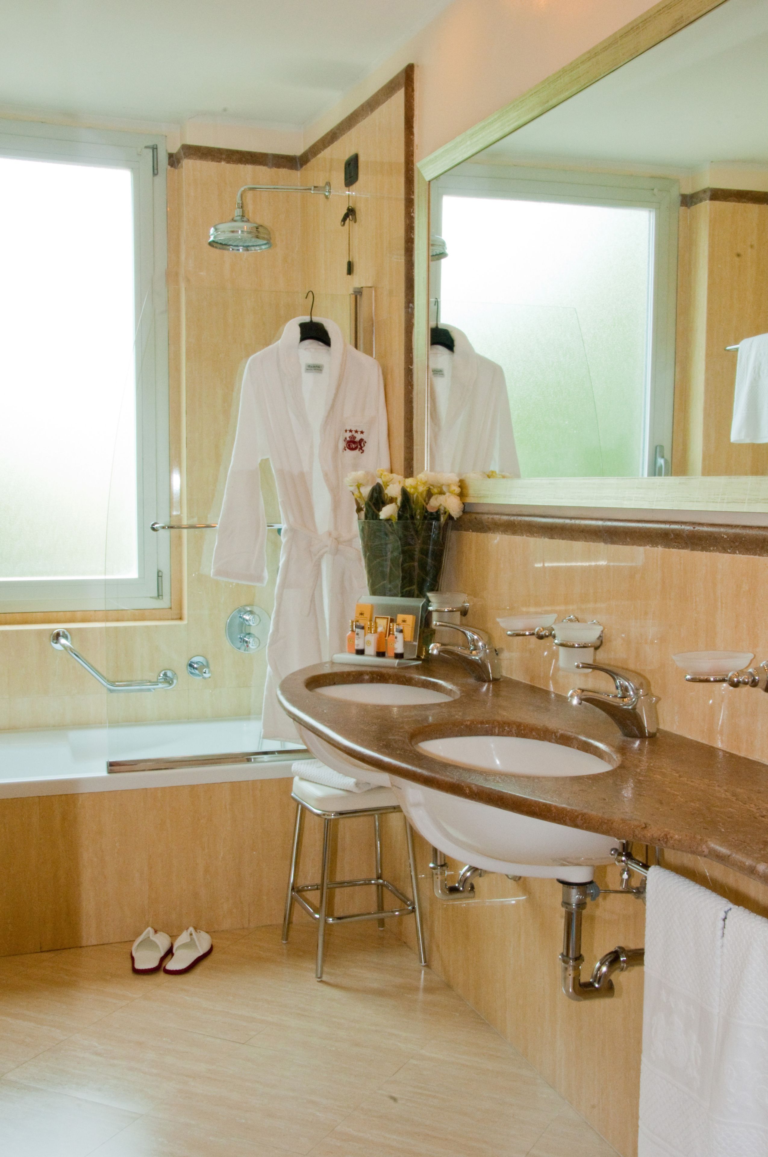 A bathroom with a large mirror, two sinks, a shower, and a vanity with a towel rack.