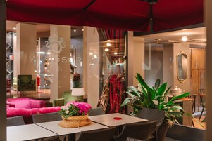 Hall d'hotel con mobili in vimini, un ombrello rosso e un cartello con la scritta 'Windsor Hotel'.