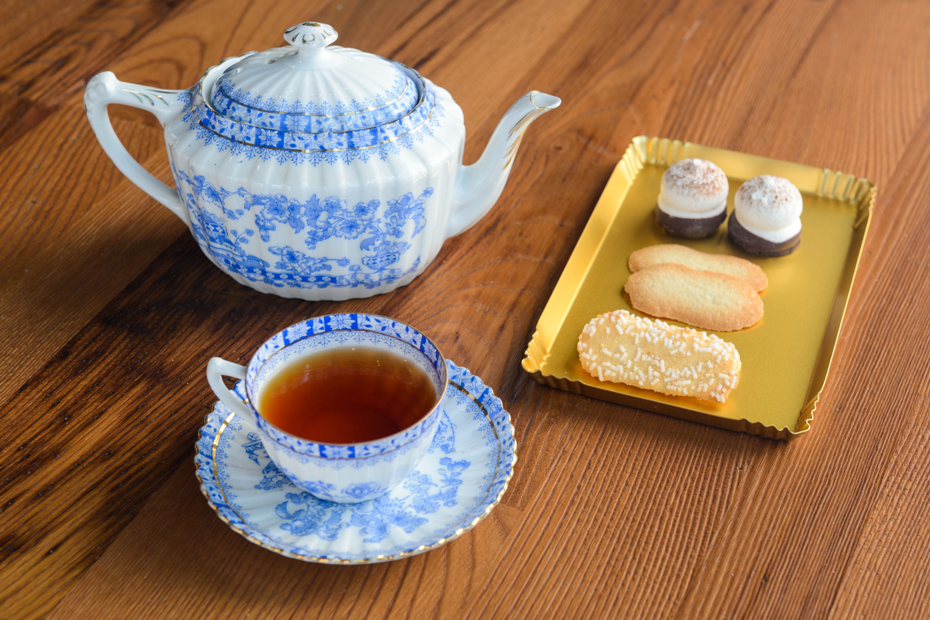 Une théière, une tasse et une assiette de biscuits sur une table en bois.