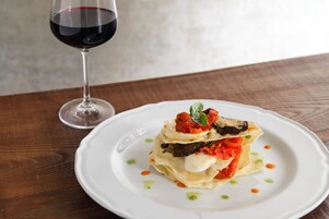 Un piatto di cibo con un bicchiere di vino rosso su un tavolo di legno.