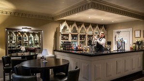 Un espace bar avec un barman, des tables rondes et un présentoir à bouteilles de vin.