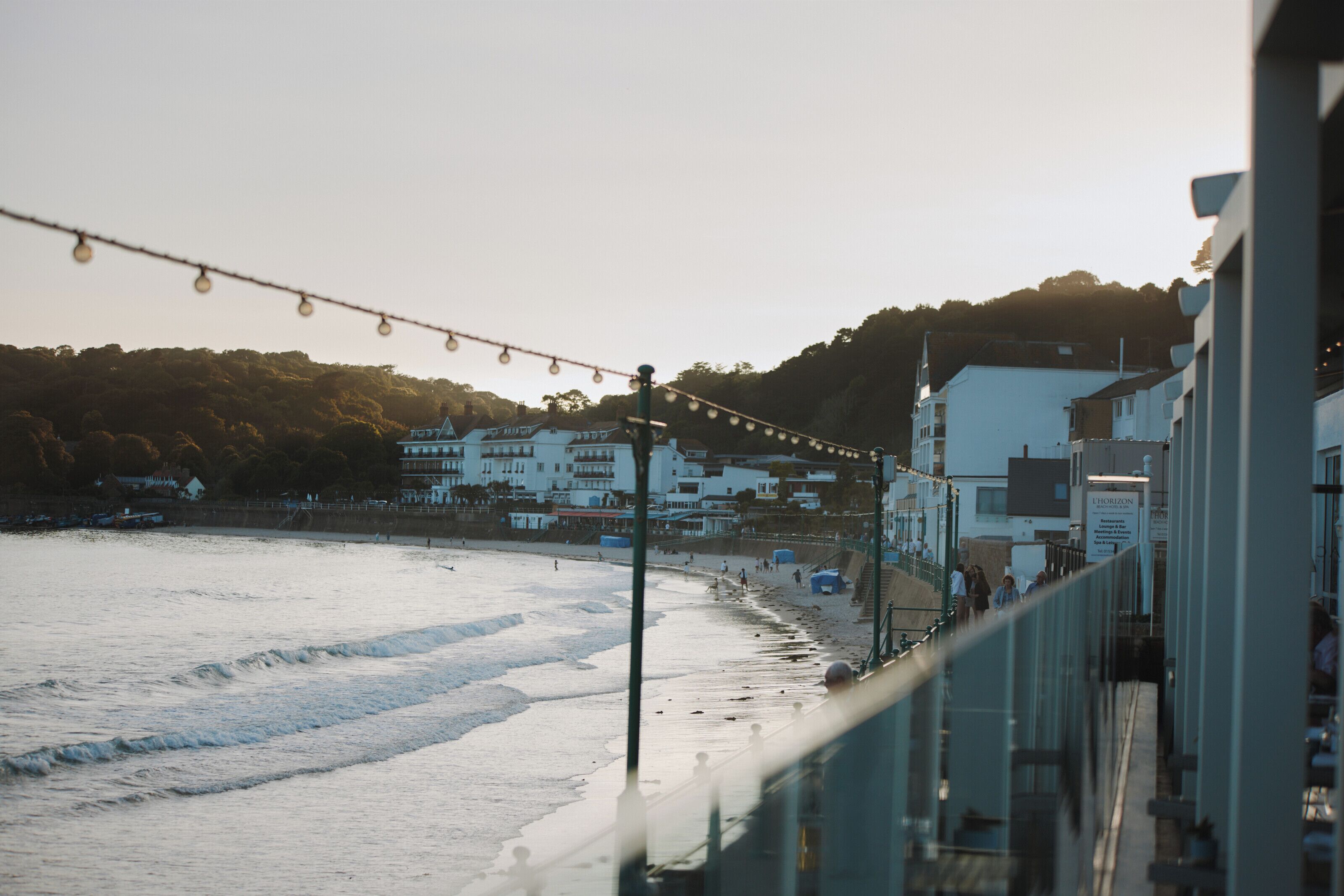 Una playa con un paseo marítimo, edificios y un cartel que dice 'HORIZON'.