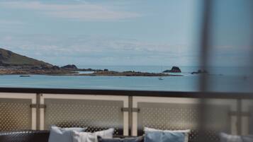 A dining area with a table set for two, overlooking a coastal landscape.