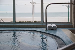 Un jacuzzi con vista a la playa, un perchero y una ventana con vistas al océano.