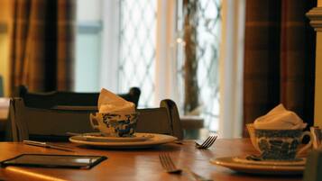 Una mesa de comedor con una taza y plato, un teléfono inteligente y un tenedor.