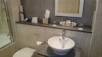 A bathroom with a white sink, a glass shower enclosure, and a toilet.