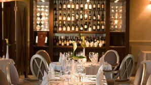 A restaurant with a long table set for dining, a wine rack in the background, and chairs around the table. - The Priest House Hotel (Derby)