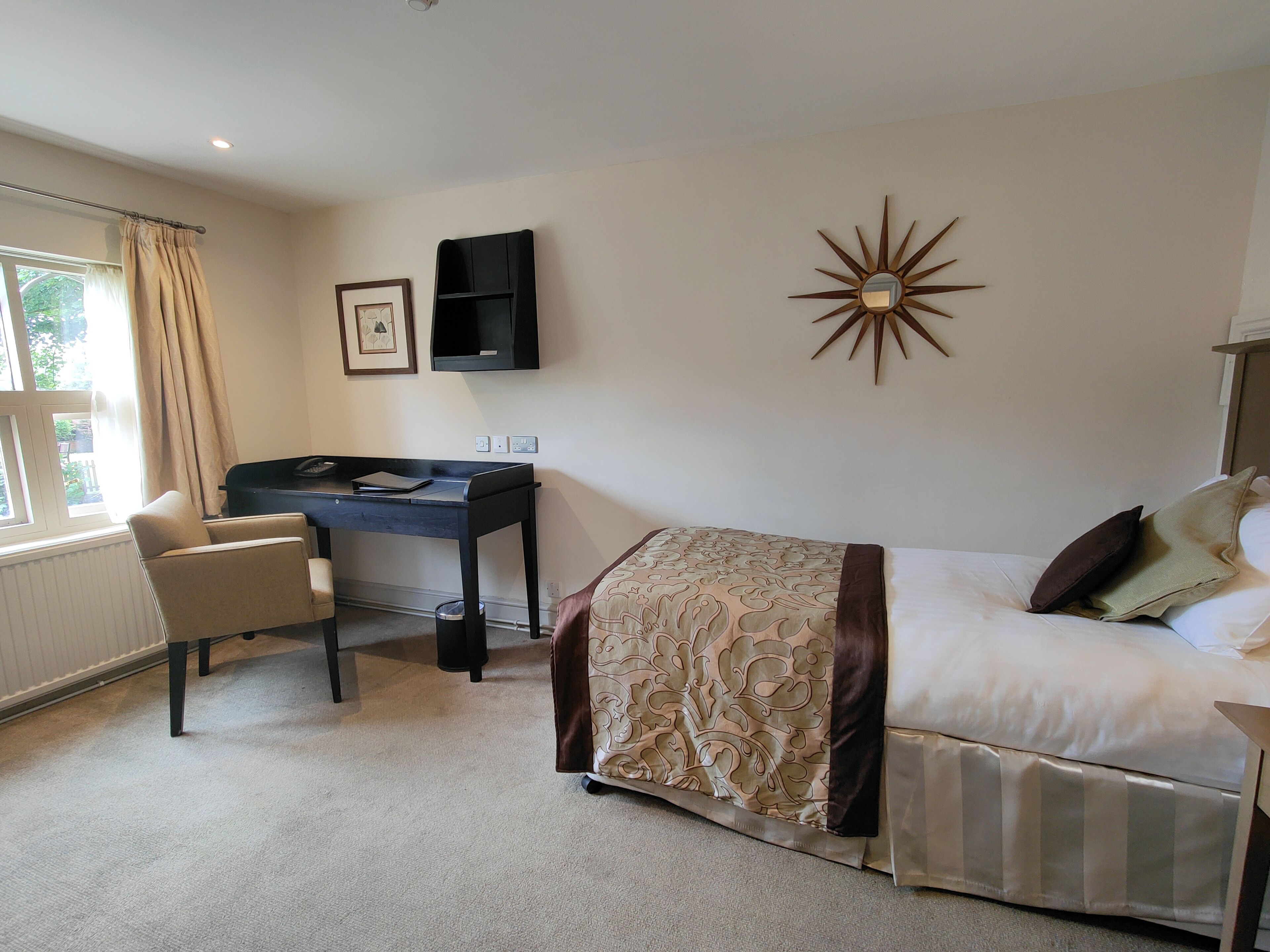 Ein Hotelzimmer mit Bett, Schreibtisch, Stuhl und einem Vorhangfenster.