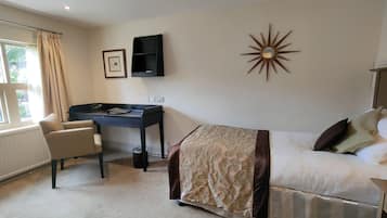 Ein Hotelzimmer mit Bett, Schreibtisch, Stuhl und einem Vorhangfenster.