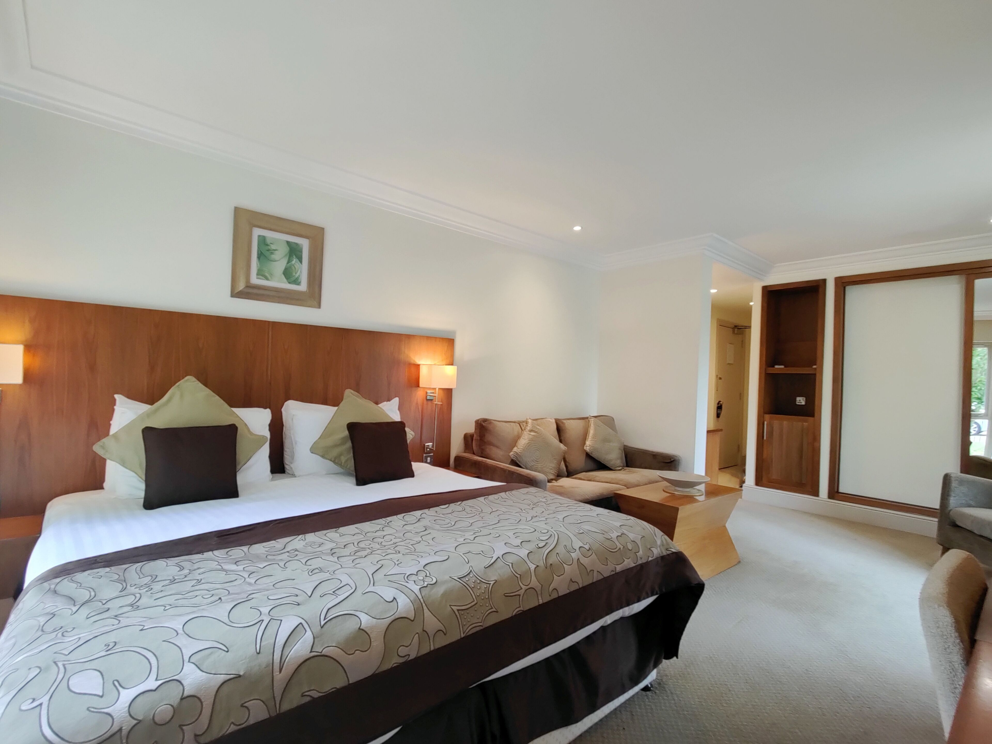 Ein Hotelzimmer mit einem großen Bett, einer Couch, einem kleinen Tisch und einem Kleiderschrank.