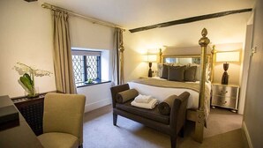 A hotel room with a large bed, a desk with a chair, a nightstand, and a window with curtains. - The Priest House Hotel (Derby)